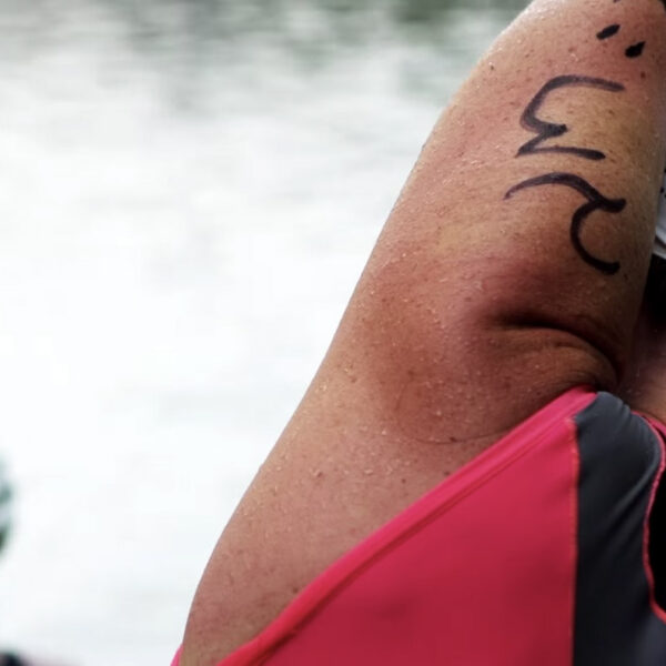 A racer stretches on the shore before the race starts.