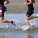 Two runners run into the shallow water to start their swim.