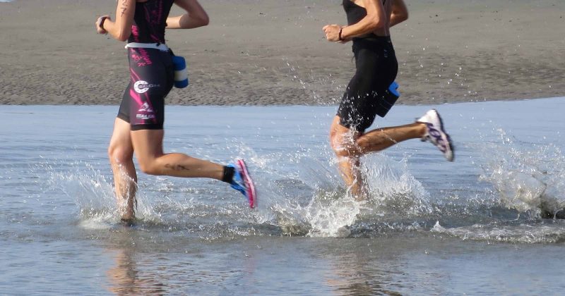 Two runners run into the shallow water to start their swim.