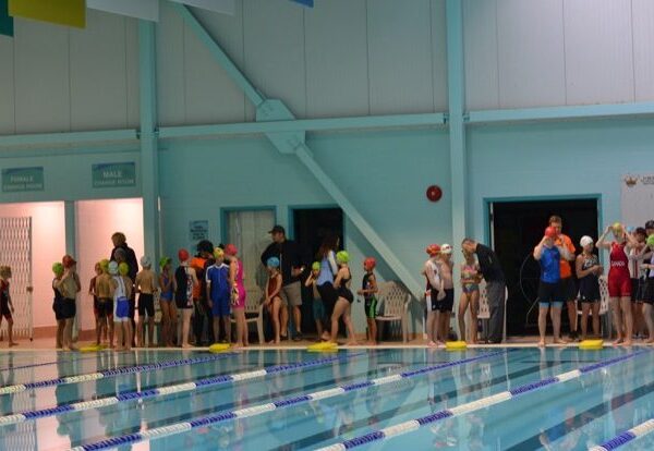 Athletes stand at the poolside waiting to start.