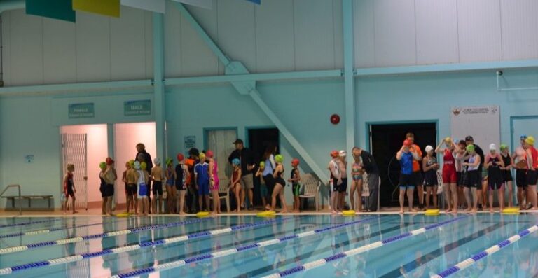 Athletes stand at the poolside waiting to start.