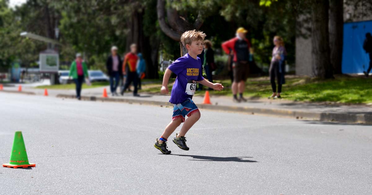 A young, and short, athlete runs out of the transition area to do a lap at the youth triathlon.