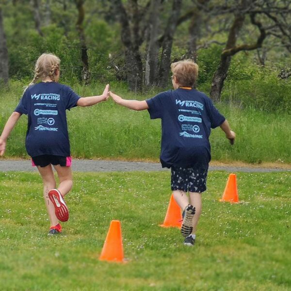 A racer shares a high five with an athlete that is already done at the youth triathlon in the West Shore.