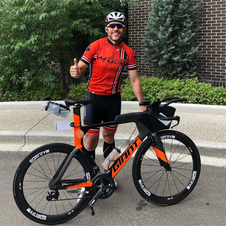 Chris Mavrikos athlete standing in front of his bike before Calgary 70.3