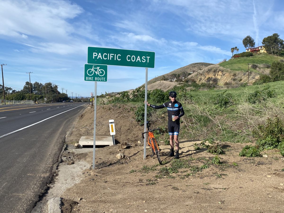 Coach Mike Neill standing next to Pacific Coast Highway sign at Vertical Camp 