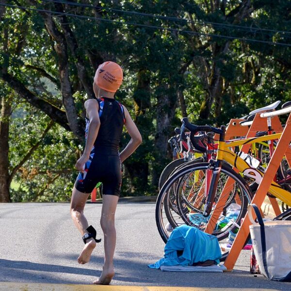 A young racer runs into the transition zone to get ready for the bike!