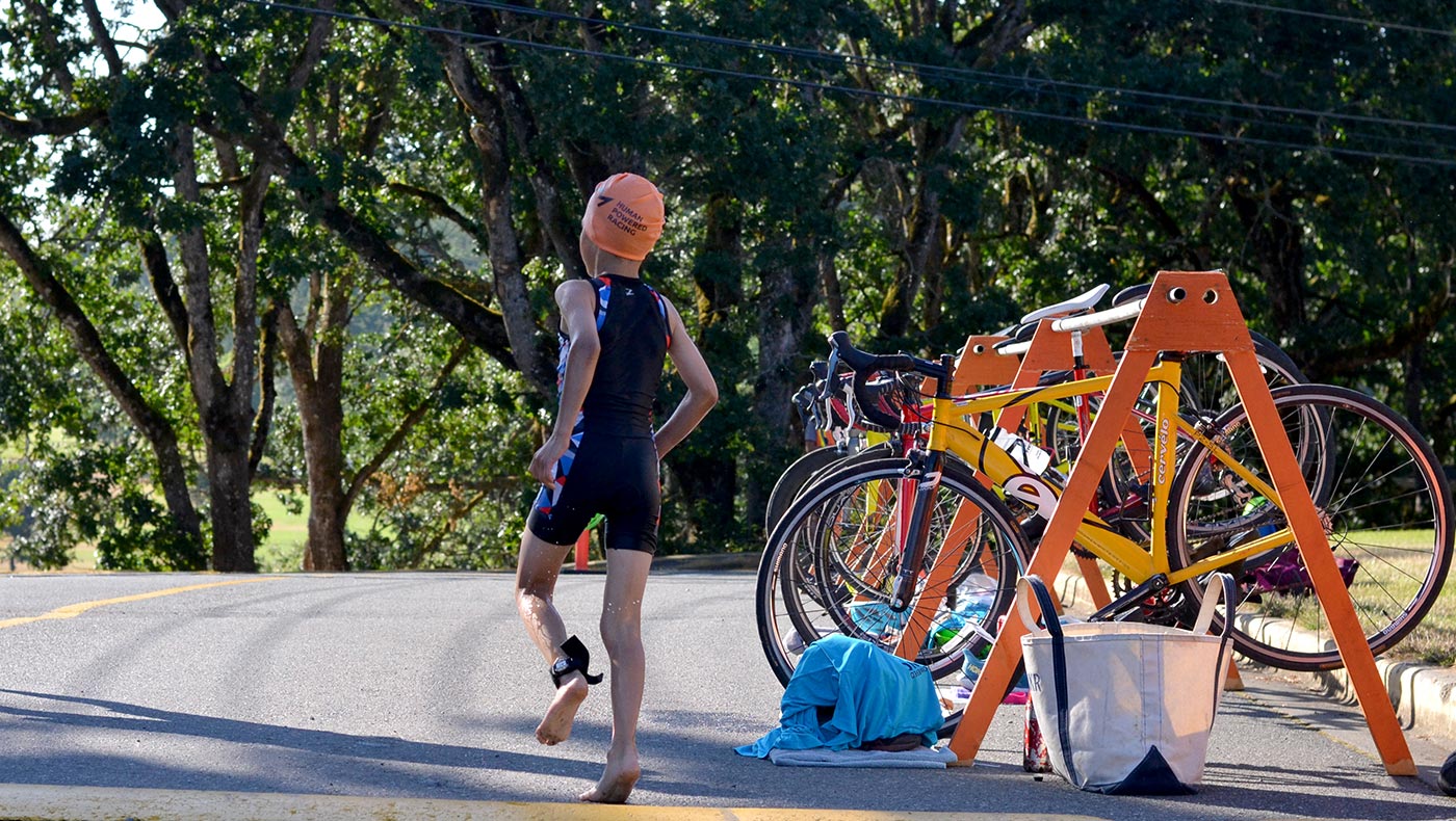 A young racer runs into the transition zone to get ready for the bike!