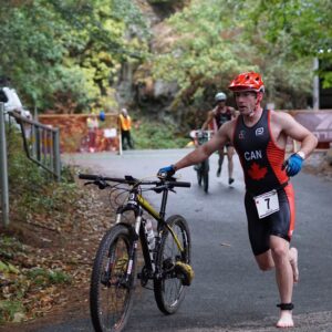 A race charges out of the transition area with his bike almost ready to get on and ride.