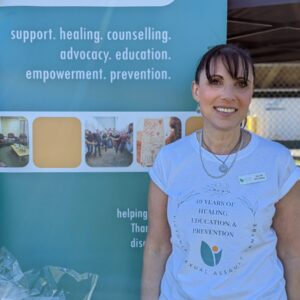 a dark haired woman standing in front of a VSAC sign