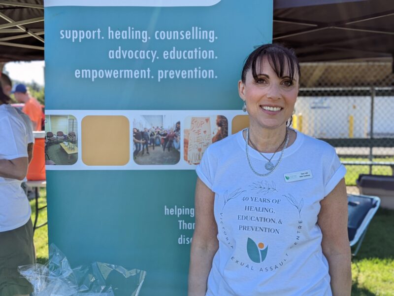 a dark haired woman standing in front of a VSAC sign