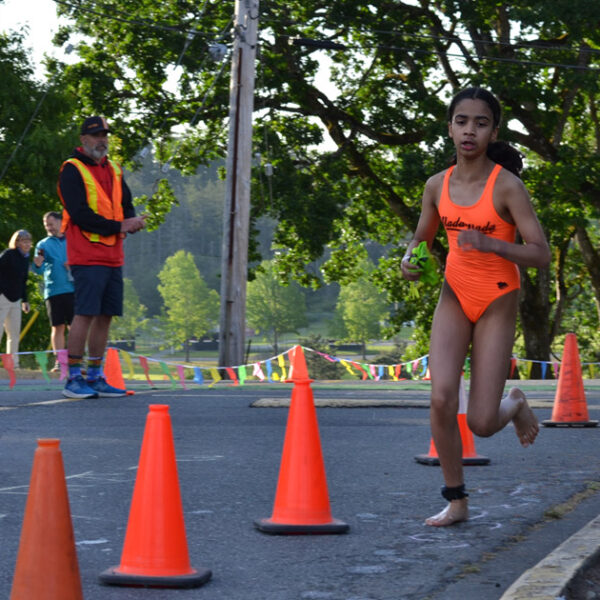 A racer charges out of the pool at Juan de Fuca Recreation centre into the transition zone, with volunteers behind her.