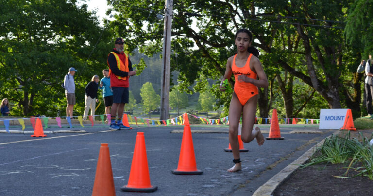 A racer charges out of the pool at Juan de Fuca Recreation centre into the transition zone, with volunteers behind her.