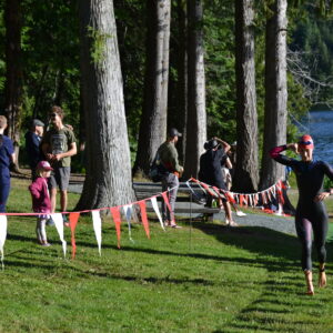 Female triathlete running up hill undoing her wetsuit.