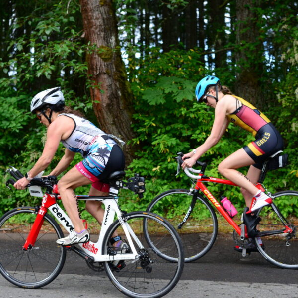 Two racers get on the bicycle and blast out of the park.
