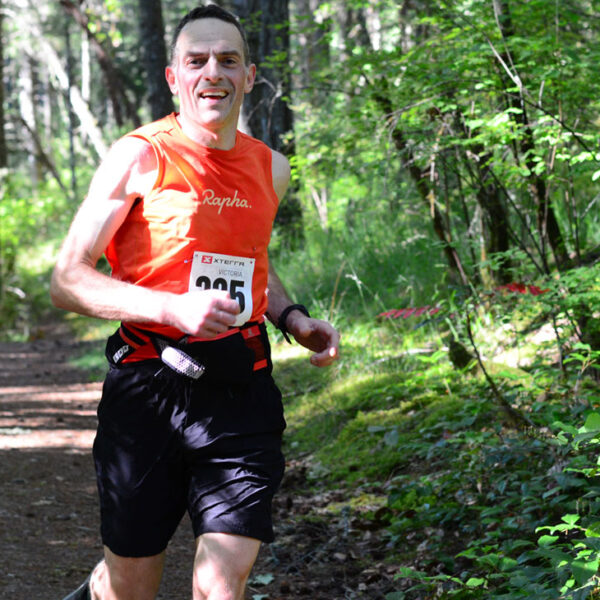 A racer blazes down a forest trailer at the beautiful XTERRA Victoria Trail Run.