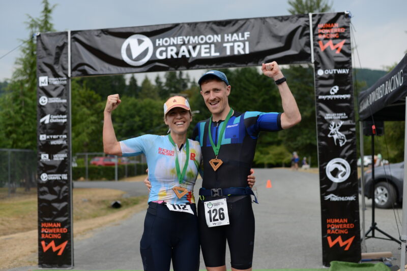 2 finishers at the finish arch at the Honeymoon Half Gravel Triathlon