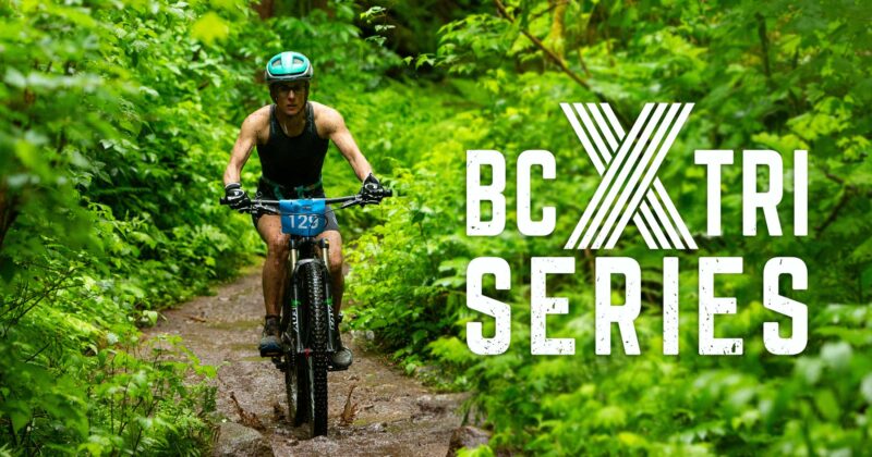 A mountain biker in a green forest with the BCX Tri logo.